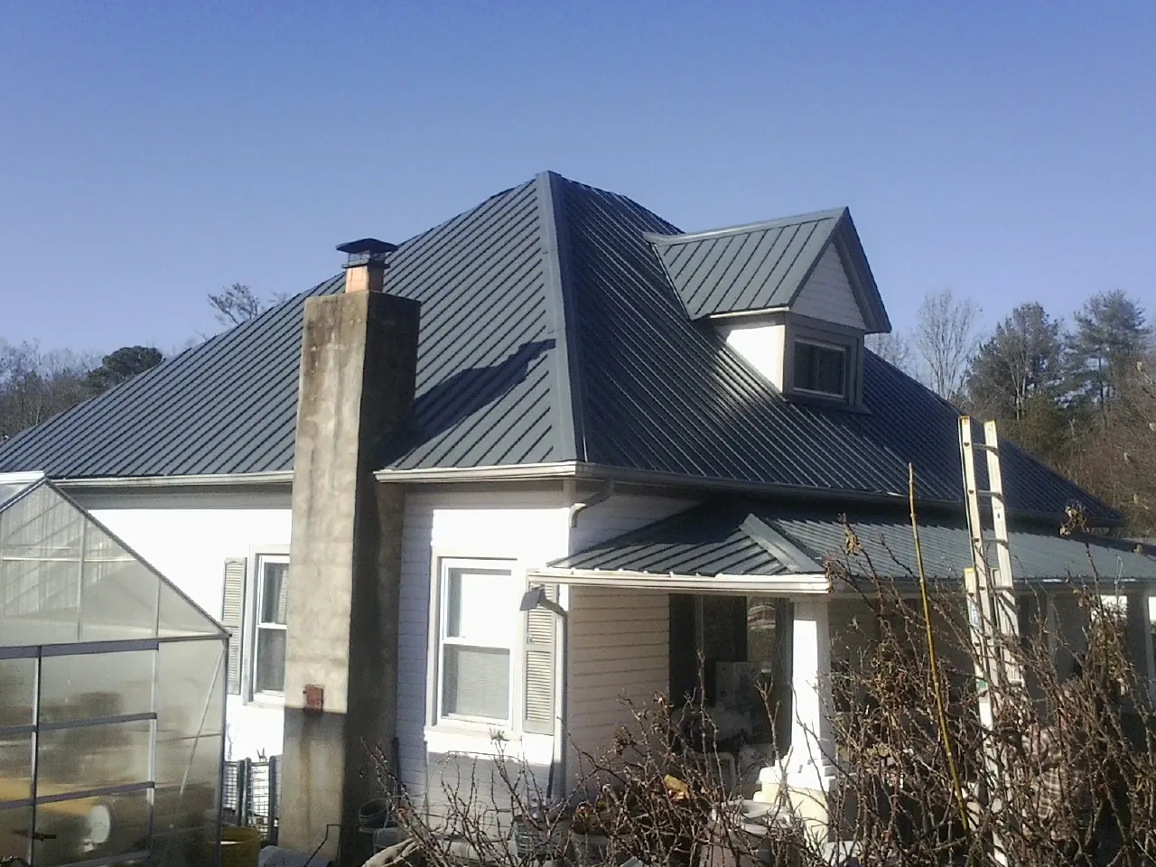 Dark blue standing seam metal roof on a white farmhouse with dormer — Slate & Tile Roof Repair by Roofing Brothers in Rexburg