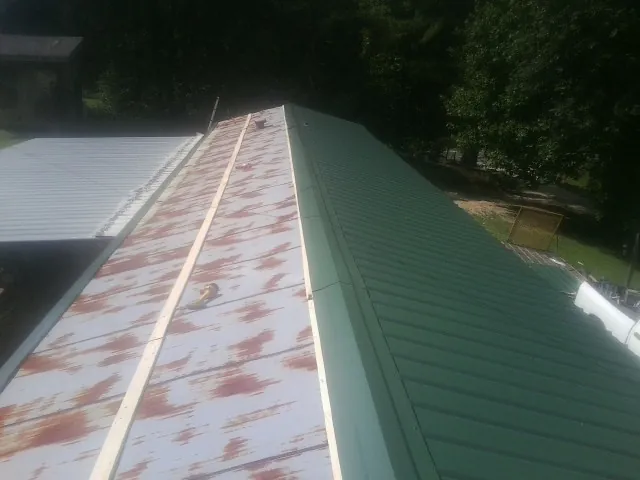 Old rusted panels beside newly installed green metal roofing — Wind Damage Roof Repair by Roofing Brothers in Rexburg