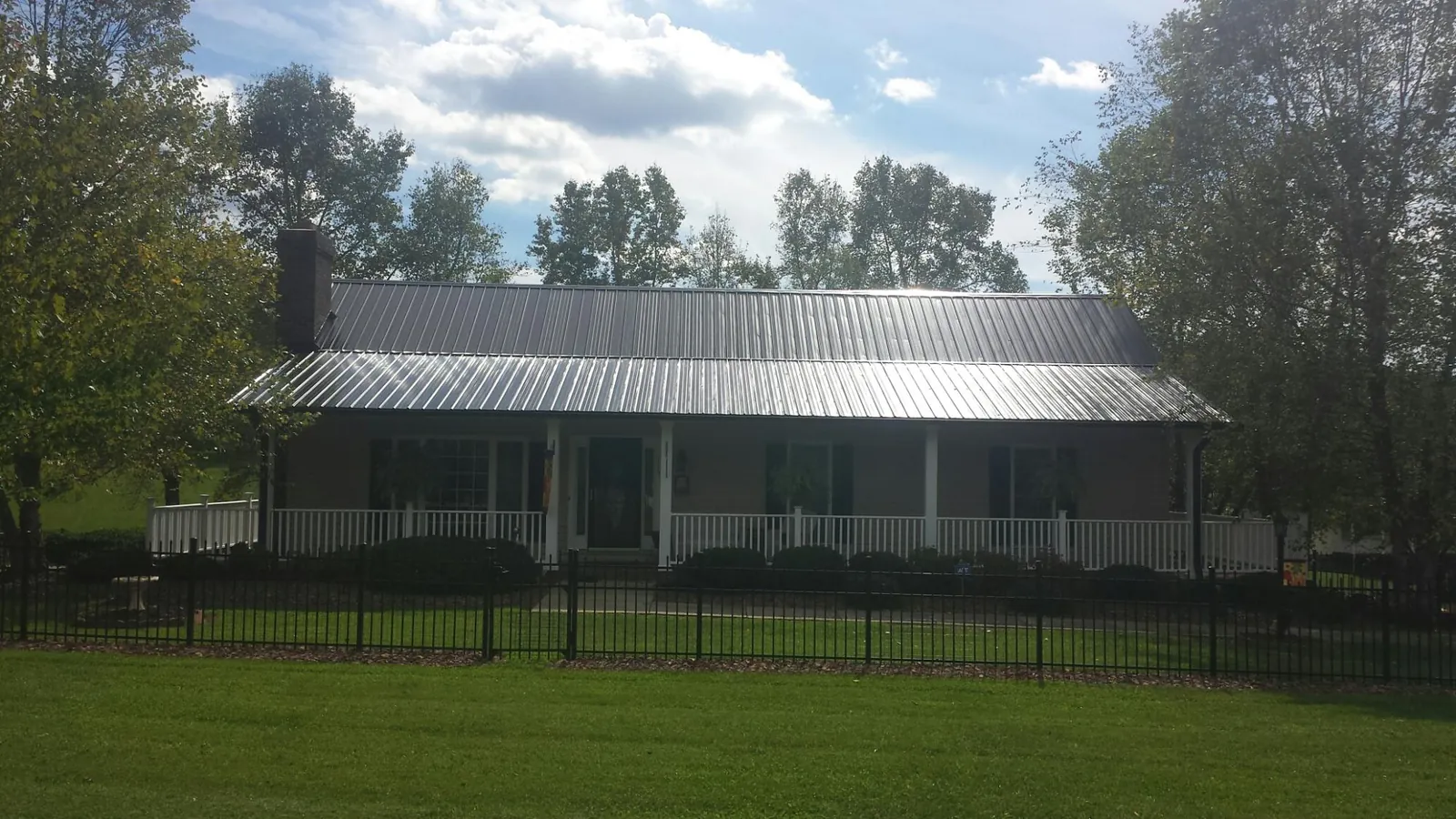 Gray metal roof on a brick ranch with a full width front porch — Gutter Guard Installation work by our crew in Rexburg